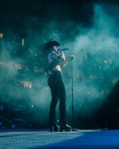 Mariah The Scientist on stage wearing a black cowboy hat, black heeled boots and partially covered by smoke effects.